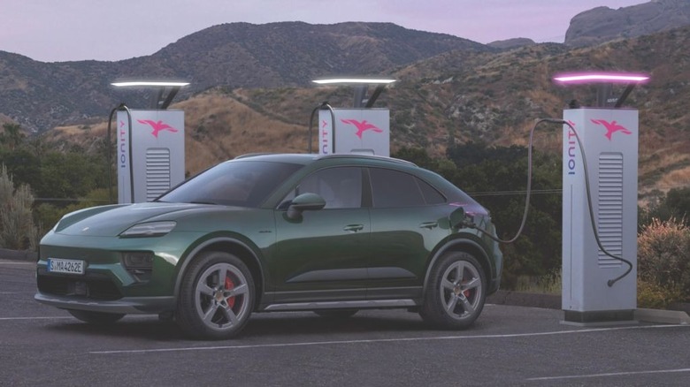 A Green 2024 Porsche Macan 4S electric, charging in front of mountains