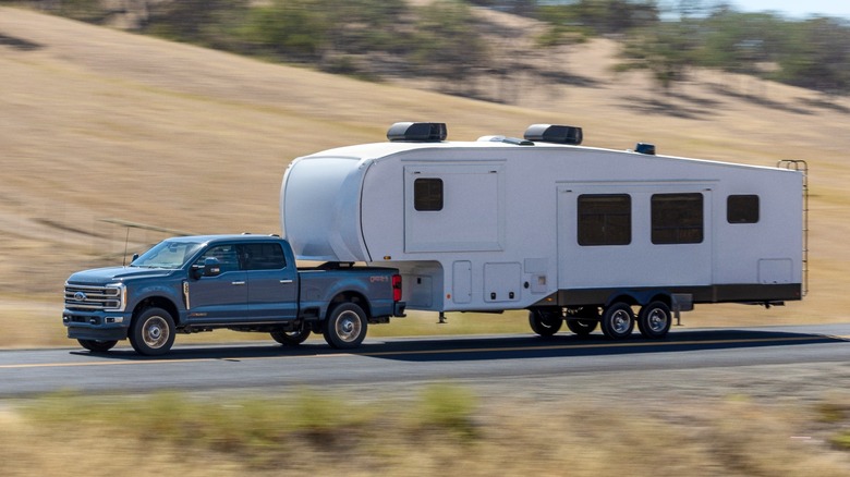 A Ford Super Duty towing a trailer down a road