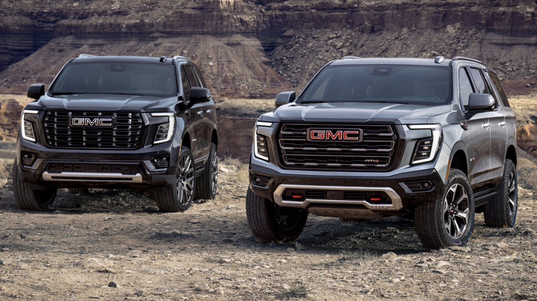 A GMC Yukon Denali Ultimate and AT4 Ultimate parked side by side in a rocky desert
