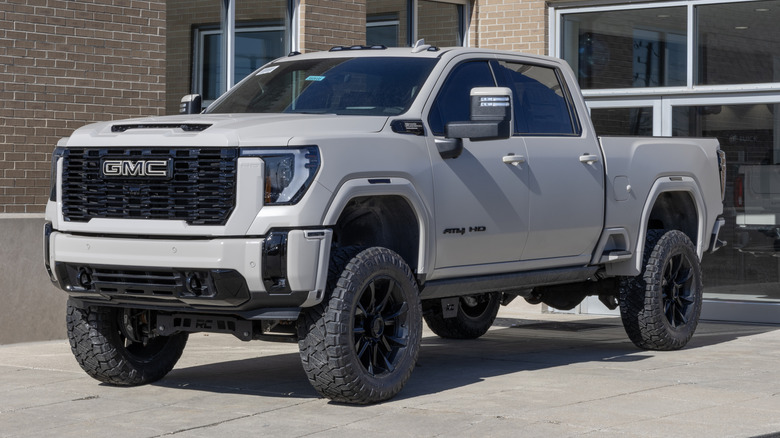 A GMC Sierra HD AT4 parked on a paved surface in front of a building