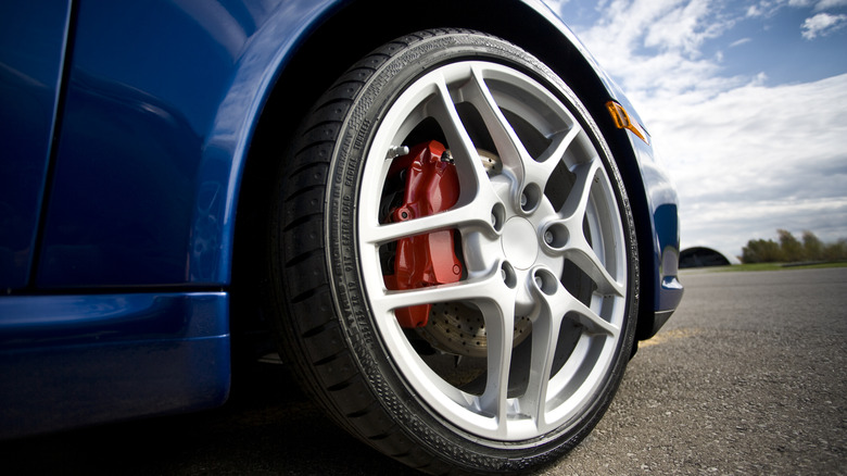 The right front wheel of a blue Porsche, shown with a performance tire.