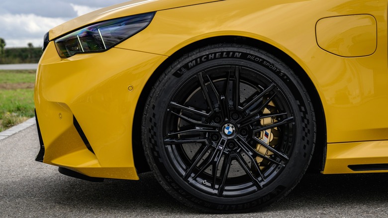 The wheel of a Speed Yellow 2025 BMW M5 is shown with M Carbon Ceramic brakes and a gold caliper.