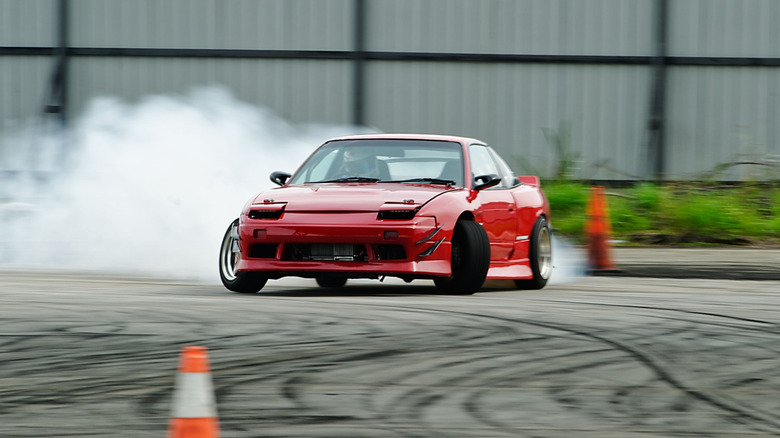 A red drift car burning rubber on the track