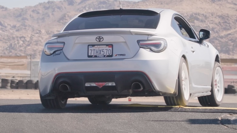 A car with independant rear suspension going over a speed bump that affects only the right wheel