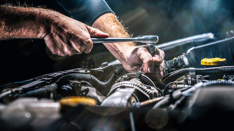 An auto mechanic working on a car engine