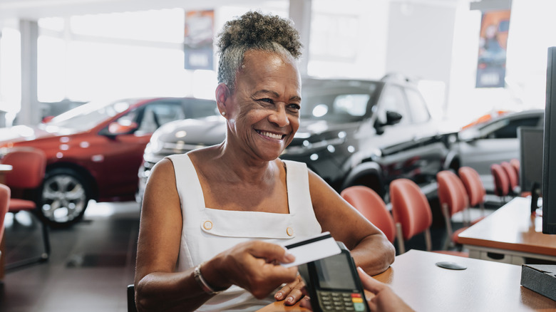 A woman paying for a car at a dealership