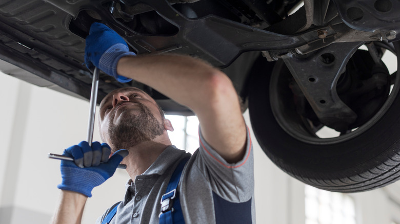A mechanic inspecting the underside of a vehicle