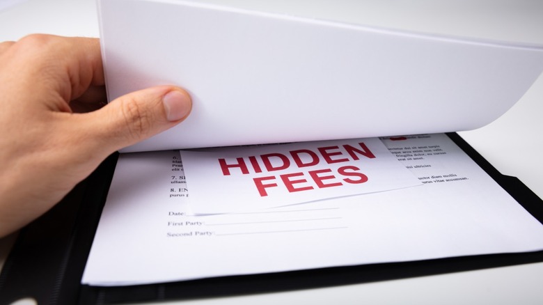 A multiple page contract with a card that says, "Hidden Fees" inside