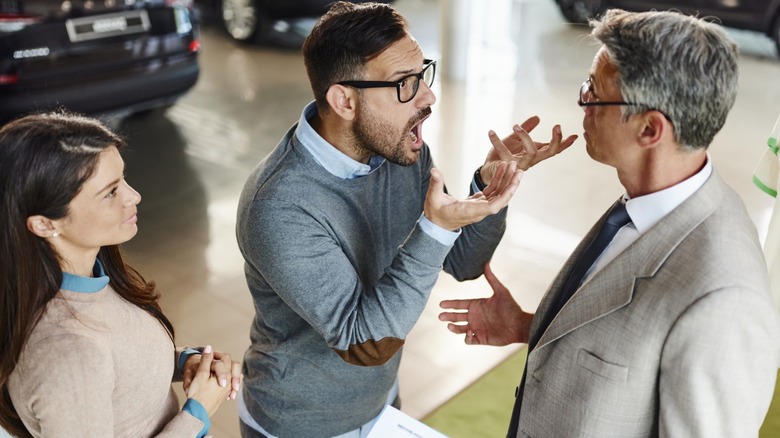 A couple arguing with a car salesman