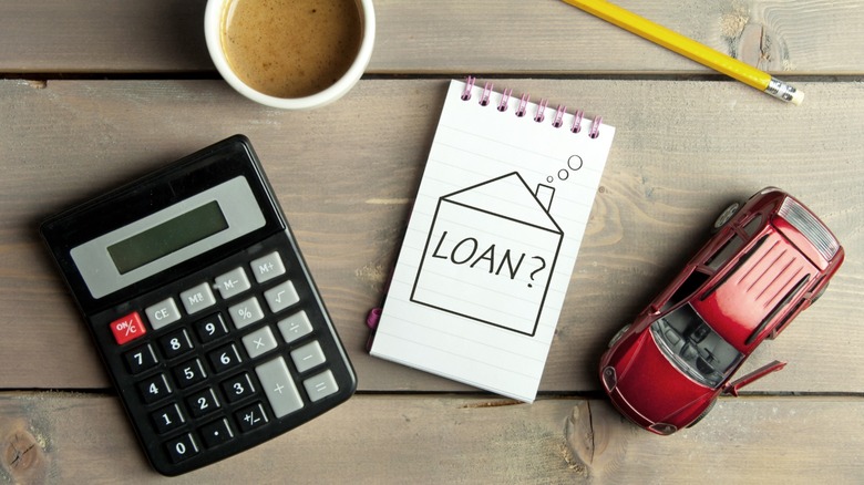 A toy car and calculator on table and a notepad that says "Loan?"