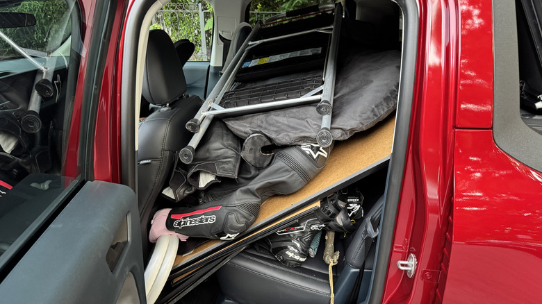 Rear seat of red Ford Maverick, full of stuff