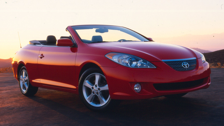 A front three quarters shot of a red 2004 Toyota Solara Convertible parked on a mountain at sunset