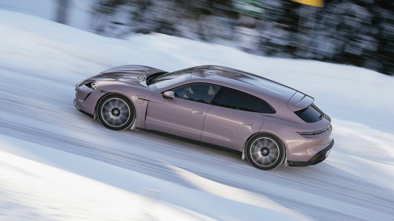A porsche taycan speeding up a snowy driving course