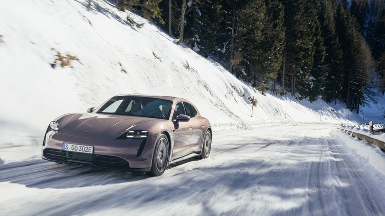 a porsche taycan driving up a snowy road