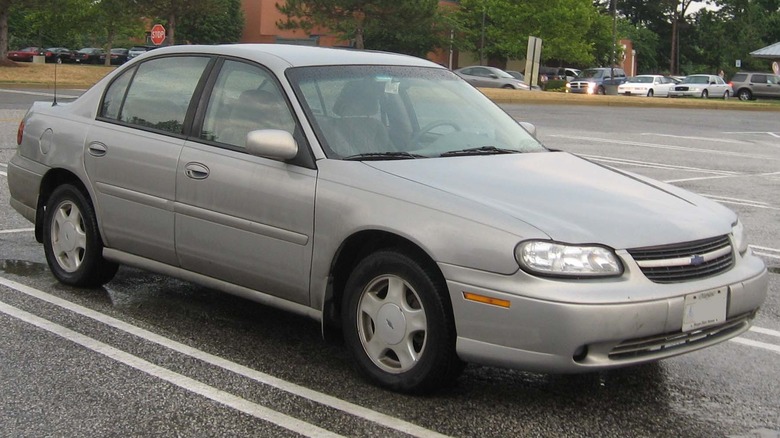 The soulless fifth generation Chevrolet Malibu in an even more soulless silver color, in a parking lot.