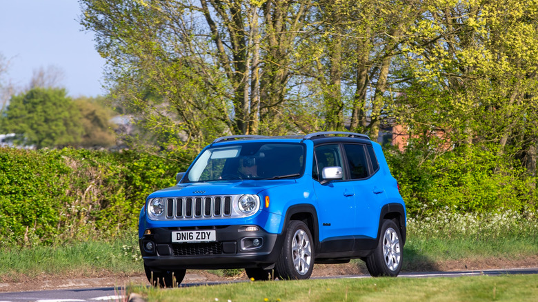 A blue jeep renegade driving around a road in england on a sunny day