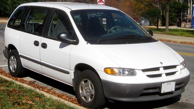 Front three-quarters shot of a white Dodge Caravan SE parked on a street next to grass