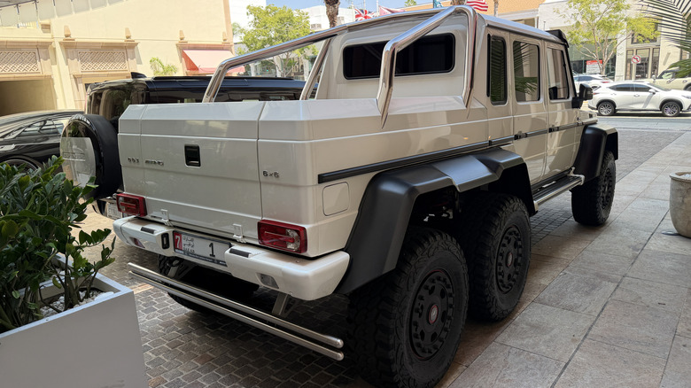 Rear 3/4 view of a white Mercedes-Benz G63 6x6 parked at a hotel