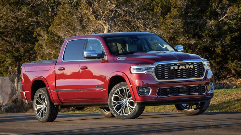 A red ram 1500 parked in front of a thicket of trees during a sunset