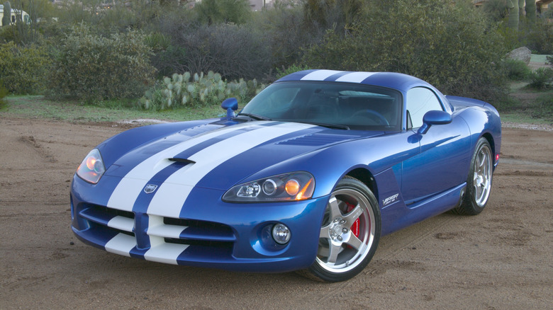 Front three-quarters shot of a blue SRT10 Viper with white stripes parked on dirt in front of shrubs and cactus