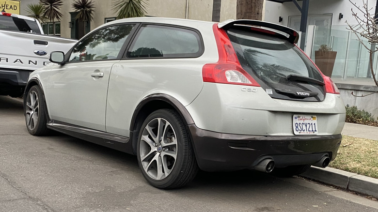 A rear three-quarters shot of a launch edition C30 parked on a street behind a white Ford Ranger