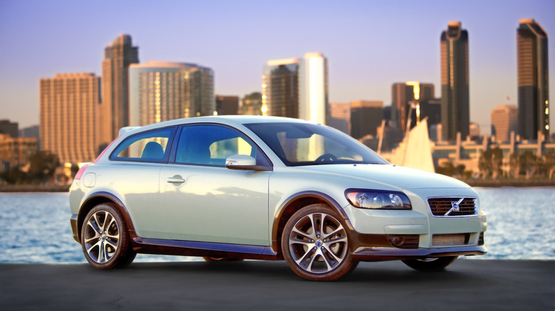 A front three-quarters shot of a Volvo C30 in its launch color scheme parked in front of water and a cityscape