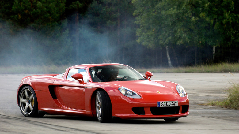 A front three quarters shot of a red Carrera GT sliding around a corner in front of trees