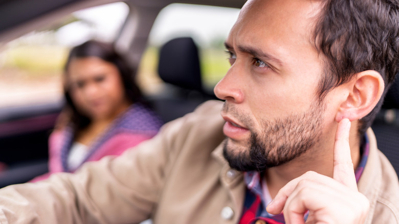 A driver paying attention to a noise coming from the car's engine