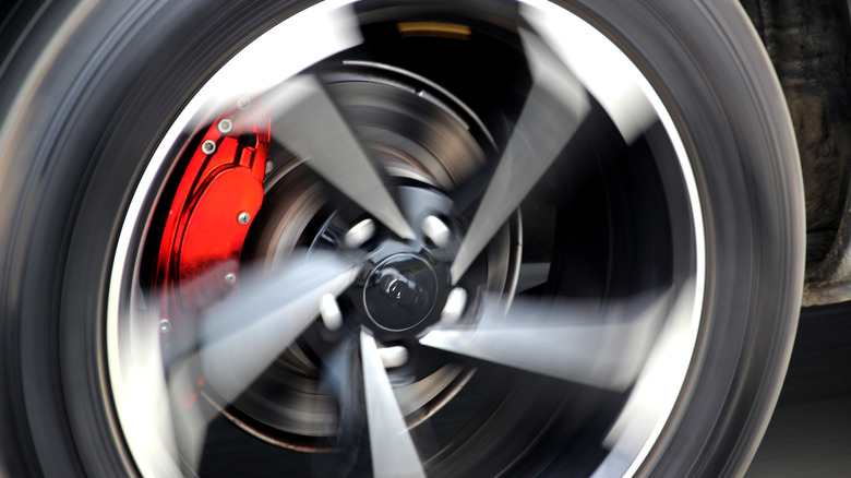 Red brake calipers behind the wheel of a fast moving car