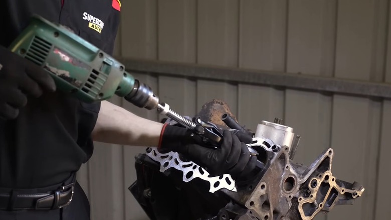 A person using a power tool to hone cylinder walls