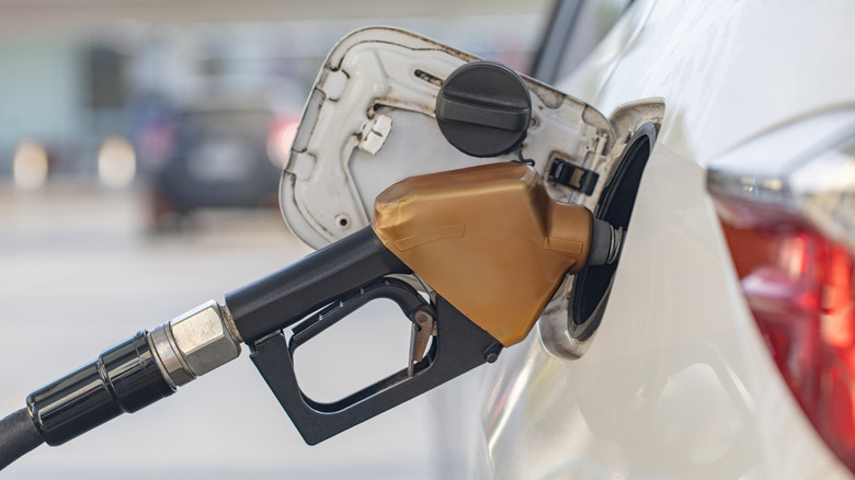 A close-up of a white car being filled with fuel at a gas station.