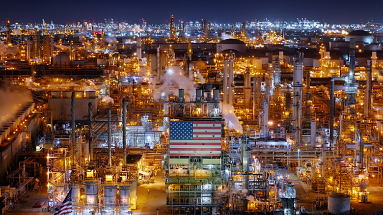 An aerial night view of an oil refinery in Wilmington with city lights in the background.