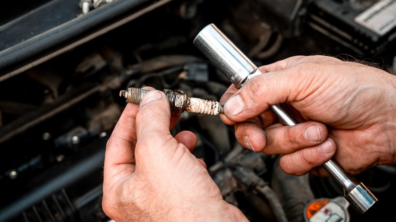 Removing an aged spark plug from an motor to switch it.