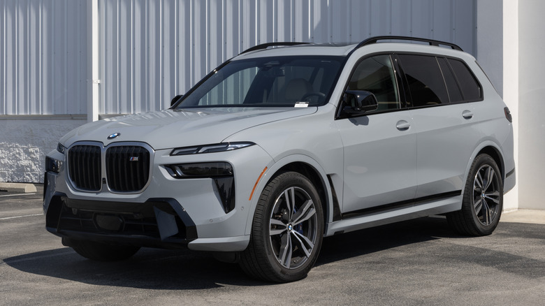 A gray BMW X7 full-size luxury SUV parked by a building