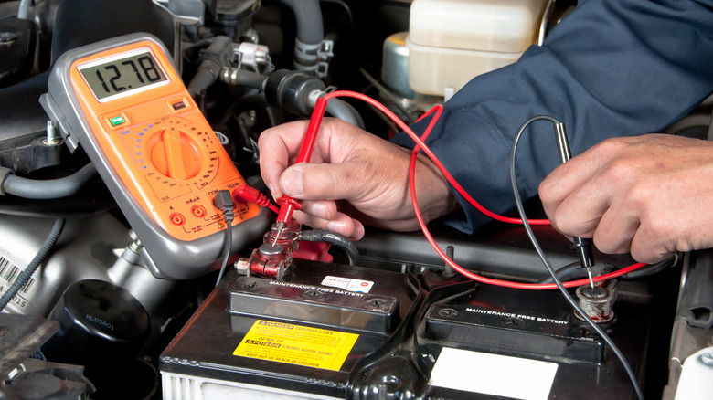 A mechanic testing a car battery