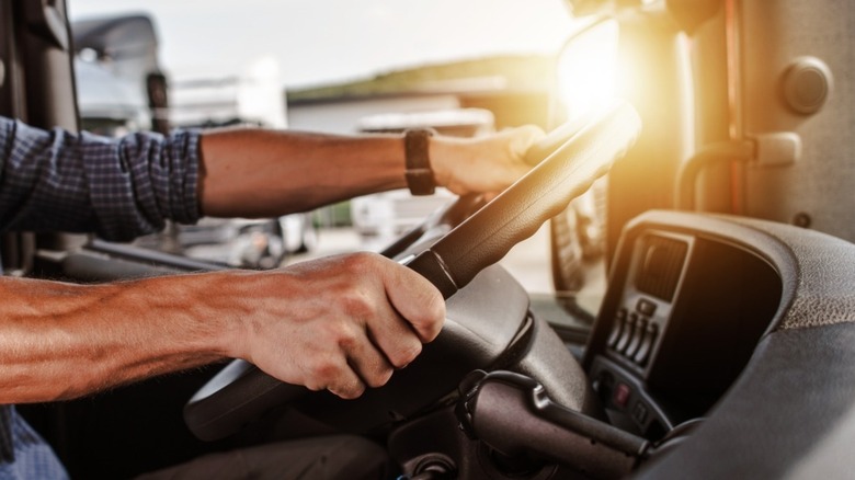 Trucker in the cab of his truck with both hands on the steering wheel