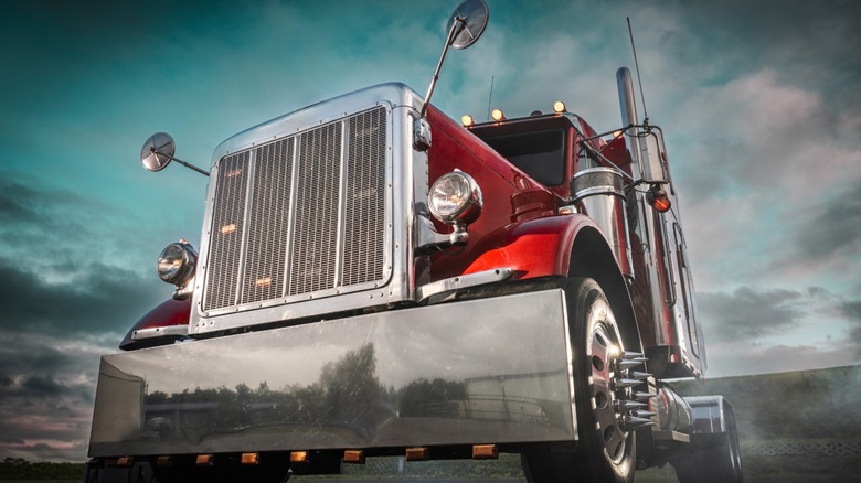 Red semi truck against a cloudy sky