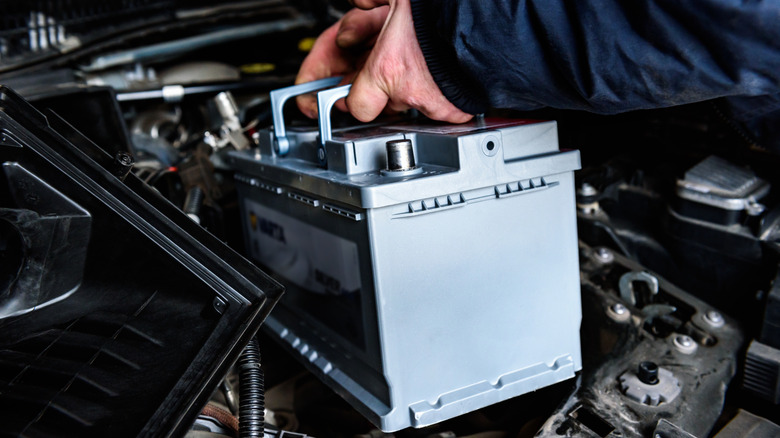 A person installing a new car battery