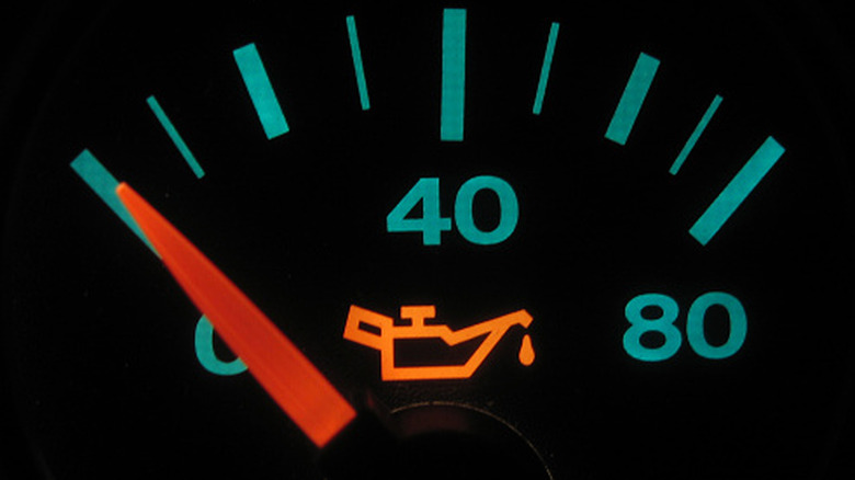 A close-up of an oil pressure gauge with the warning light on.