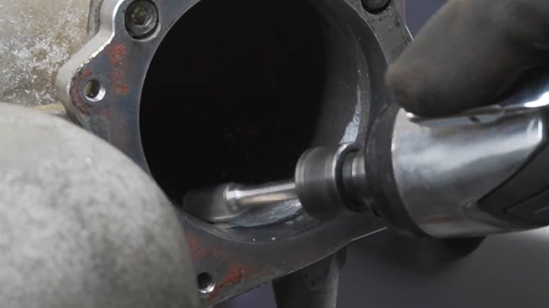 A mechanic porting an intake manifold using a small grinding tool