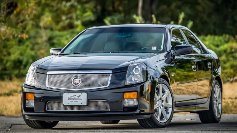 A black first generation Cadillac CTS-V parked in front of out-of-focus bushes