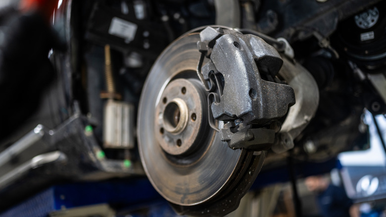 An exposed car brake rotor and caliper in a workshop