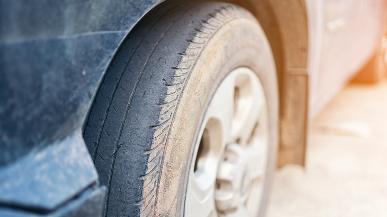 A closeup of a worn front tire on a car