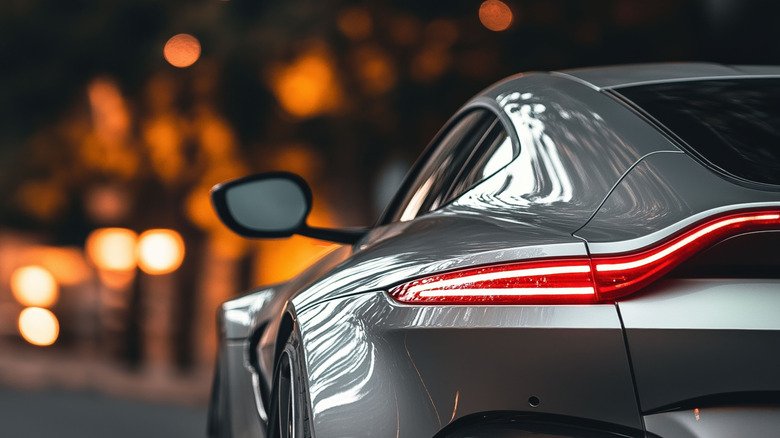 A rear quarter-end view of an Aston Martin Vantage under night city lights.