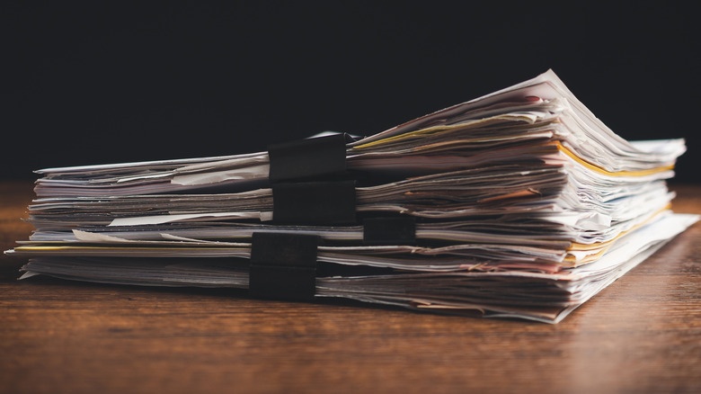 A large stack of papers in folders and bound by binder clips.
