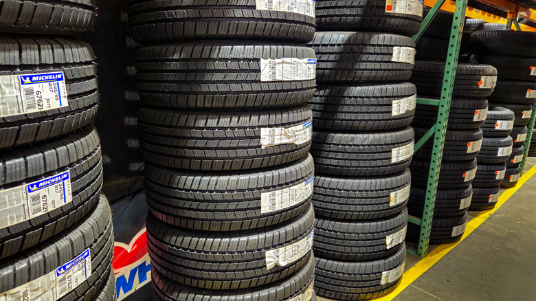 Rows of tires stacked high for sale in a Costco wholesale store with a visible Michelin brand logo.
