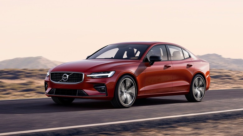 Front three quarters shot of a red Volvo S60 driving on asphalt in a desert