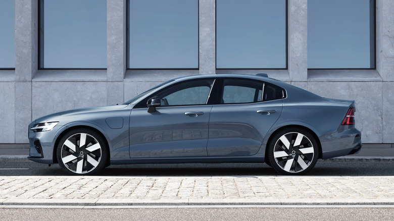 Pogled sa strane na sivu limuzinu S60 parkiranu pored cigli ispred zgrade sa zrcalnim prozorima