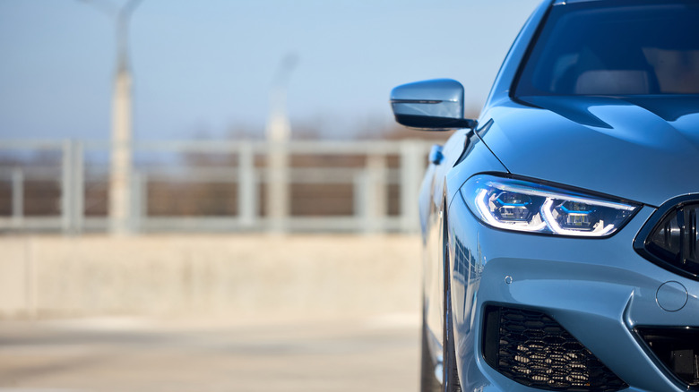 A BMW 8-series sits in front of a blurred-out sidewalk with railings
