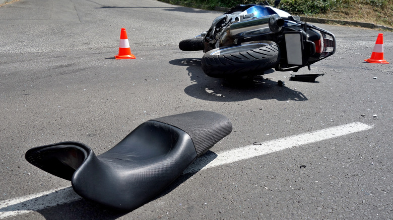 A motorcycle crashed on a sunny day, with safety cones set up around it